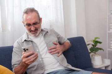 Elderly man experiencing chest pain while using smartphone at home, symbolizing heart attack...