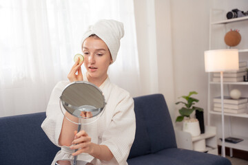 Woman enjoying home spa with cucumber slices on eyes and towel on head. Concept of skincare,...