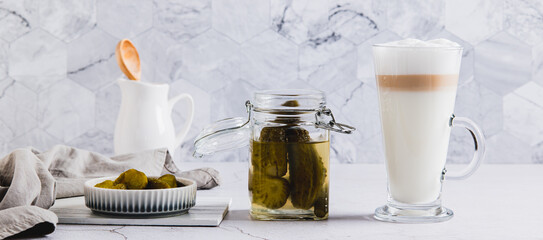 Latte with pickles in a glass and pickles in a bowl on the table web banner