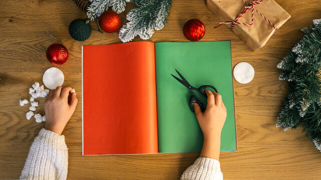 Christmas crafts with scissors and colorful paper on a wooden table