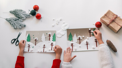 Children crafting winter landscape Christmas cards with ornaments and gifts