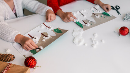 Children crafting a winter mountain scene with cotton balls and paper