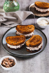 Ricotta and tuna salad on a grain bread burger on a plate on a table vertical view