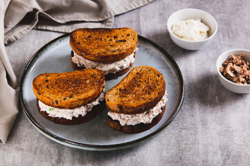 Ricotta and tuna salad on a grain bread burger on a plate on a table