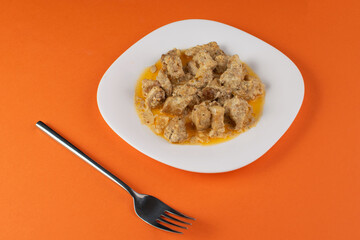 Delicious Beef Stew on White Plate with Fork on Vibrant Orange Background