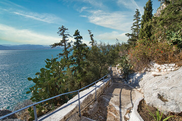 Scenic coastal path with sea view and lush vegetation in Nafplio, Peloponnese, Greece