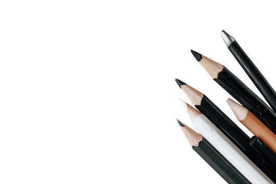 Assorted pencils and pens clustered in a corner against a black background