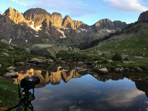 Camera capturing sunrise reflection in Pyrenees mountains
