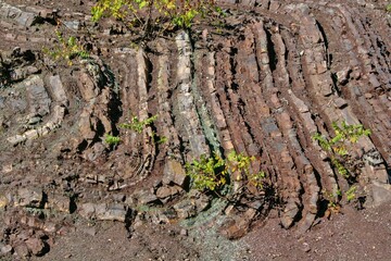 Layered rock formations of the Zagros Mountains, featuring distinctive red and green sedimentary strata under a clear sky in Kurdistan