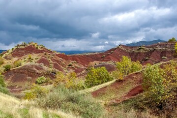 Layered rock formations of the Zagros Mountains, featuring distinctive red and green sedimentary strata under a clear sky in Kurdistan