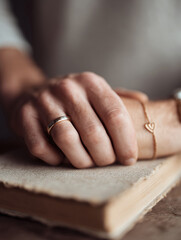 Obraz premium Hand resting on an antique book, symbolizing knowledge, love, and commitment. Minimalist, soft focus. Ideal for themes of history, relationships, or personal stories.