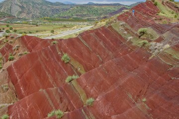 Layered rock formations of the Zagros Mountains, featuring distinctive red and green sedimentary strata under a clear sky in Kurdistan