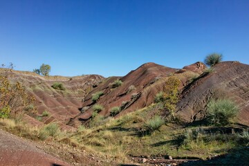 Layered rock formations of the Zagros Mountains, featuring distinctive red and green sedimentary strata under a clear sky in Kurdistan