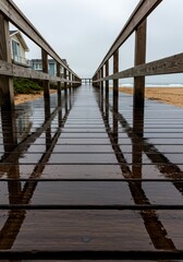 Wet wooden planks of a coastal boardwalk reflecting the sky and surrounding structures after a rain shower in soft light, horizontal, moody, perspective