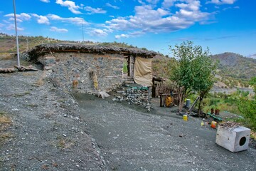 Traditional rural life in a Kurdish village, featuring a weathered stone and wood shelter and a dirt path