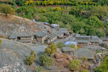 Traditional rural life in a Kurdish village, featuring a weathered stone and wood shelter and a dirt path