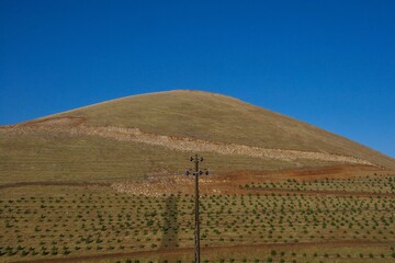 Layered rock formations of the Zagros Mountains, featuring distinctive red and green sedimentary strata under a clear sky in Kurdistan