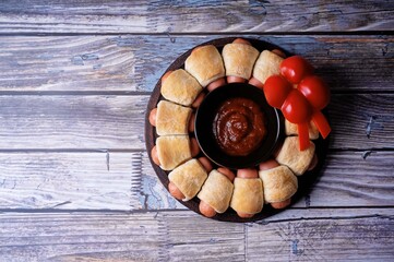 Sausages in dough in the form of Christmas wreath with ketchup sauce for Christmas holidays