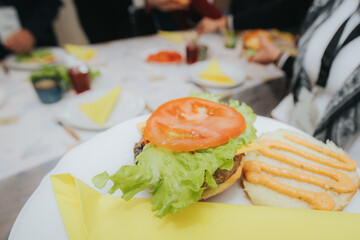 An open-faced burger with a grilled patty, melted cheese, and creamy sauce on a bun, served on a plate with a yellow napkin, ready to be assembled and enjoyed.