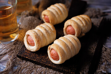 Sausage in dough, hot dog bread mini in a plate on a wood background
