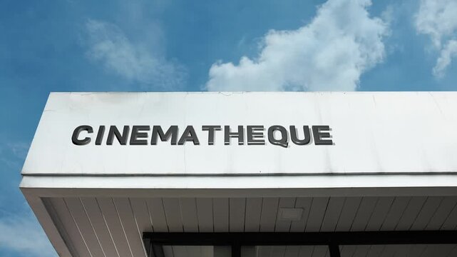 Cinematheque word sign prominently displayed on the cultural, institutional facade beneath a clear blue sky, signifying a specialized archive and screening venue for classic and art films