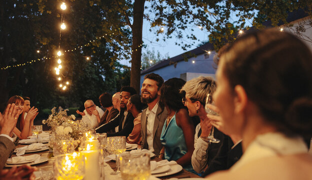 Outdoor evening wedding reception with guests dining under string lights