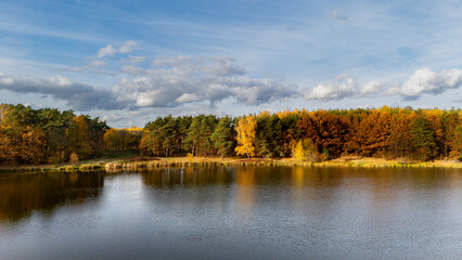 Fototapeta premium Autumn lake with colorful forest and cloudy sky