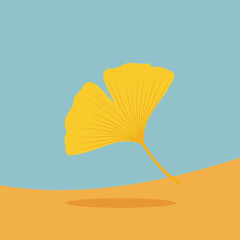 A single yellow ginkgo leaf floats above a yellow surface casting a shadow.