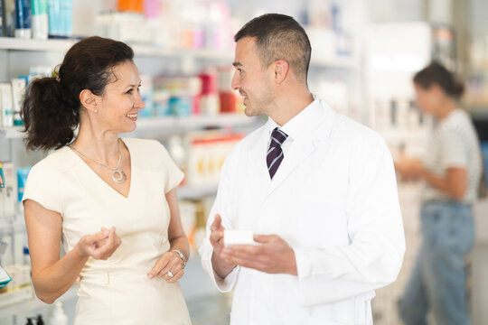 Polite male pharmacist consulting woman customer about medicament in box in chemist's shop
