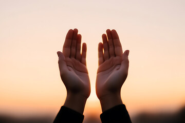 Hands raised to the sky, silhouetted against a warm sunset, expressing gratitude or seeking blessings. The soft light creates a sense of hope and connection. Golden hour prayer.