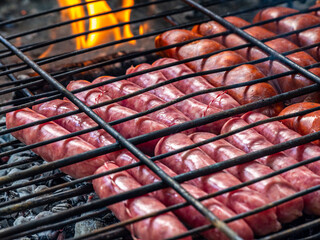 Grilled Spanish sausages (chorizo and longaniza) cooking over hot embers on a barbecue grill, traditional Mediterranean cuisine and outdoor food in Spain.