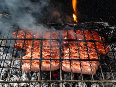 Grilled Spanish sausages (chorizo and longaniza) cooking over hot embers on a barbecue grill, traditional Mediterranean cuisine and outdoor food in Spain.