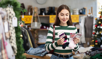 Woman client looks at products in store, looks closely at socks, picks up wardrobe item. Concept of...