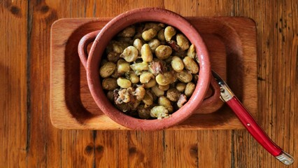 Traditional Abruzzo recipe with broad beans, pancetta, and pecorino cheese, served in a rustic terracotta pot on a wooden table. Authentic homemade Italian countryside food