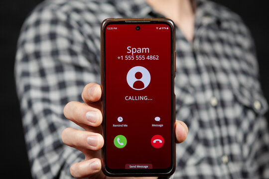 a man showing a smartphone with a warning of a spam incoming call