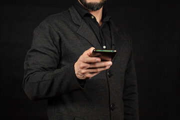 a modern business man holding a smartphone with his right hand in front of him and a black background