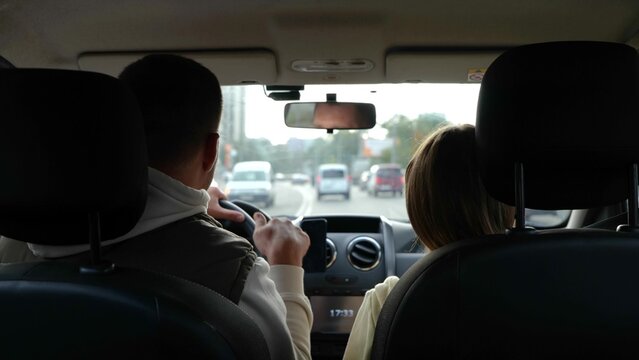 Adult man driving car and dancing with little teen daughter moving hands to rhythm. Close up of father with kid girl in vehicle during travel. Fun, road trip. Back view.