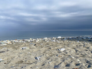 Cloudy beach with rocky shoreline and calm sea under overcast sky