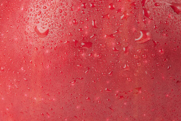 Texture of red ripe apple with drops as background.