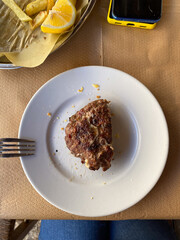 Grilled hamburger patty on plate with fries and lemon on table