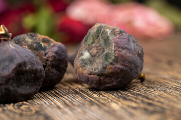 whole overripe and spoiled figs on the table, moldy spoiled figs on the wooden table