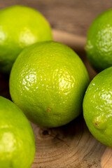 green citrus limes scattered on a wooden table in the kitchen, ripe and juicy lime fruits for cooking both sauces and drinks and other food