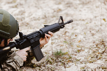 Soldier in tactical gear aims a rifle.