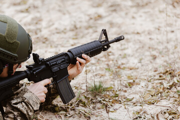 Soldier in tactical gear aims a rifle.