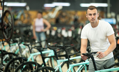 Obraz premium Young man buyer chooses bicycle in sports store