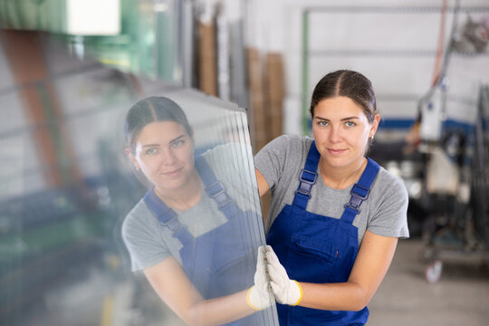 Female foreman inspecting plate glass cut to size in factory