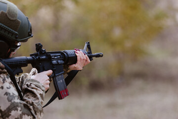 A woman in camouflage aims a rifle.