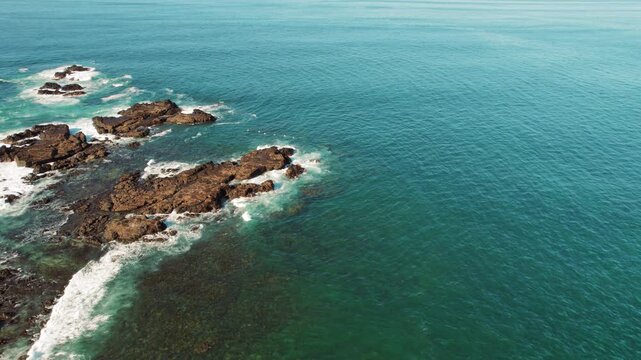 Aerial view flock of pelicans flying over rocky formations and ocean, Costa Rica