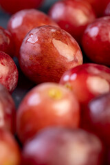 torn red ripe grapes in drops of water on a blue plate , wet and delicious red grapes on a plate on a black slate board