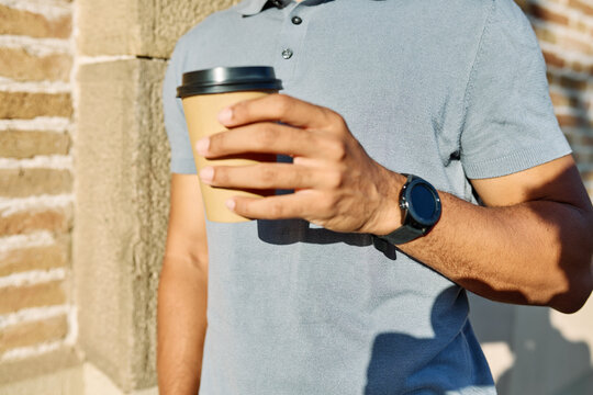 Smiling man enjoying coffee outdoors in the city on a sunny day